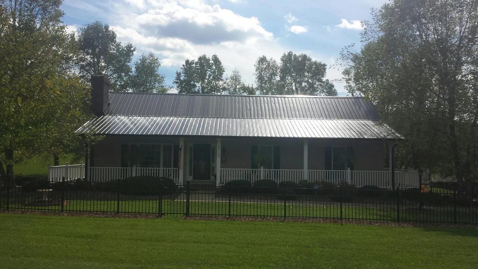 Gray metal roof on a brick ranch with a full width front porch — Gutter Guard Installation work by our crew in Westmoreland